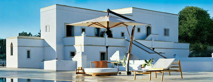 Parasol haut de gamme design avec structure déportée, offrant de l’ombre à un salon de jardin moderne près d’une piscine.