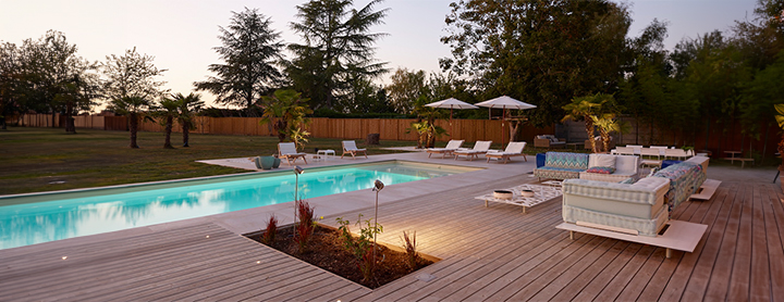 Piscine contemporaine avec terrasse en bois, transats et mobilier de jardin haut de gamme dans les Yvelines.