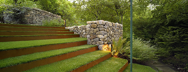 Muret de jardin en pierre naturelle avec escalier paysager et éclairage intégré.